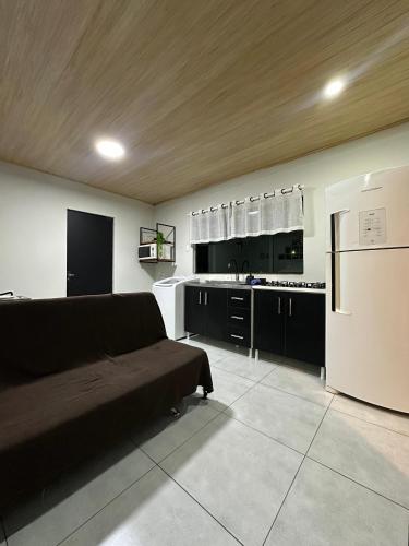 a living room with a couch and a kitchen at LOFT Completo - próximo ao Centro com Ar Condicionado in Joinville