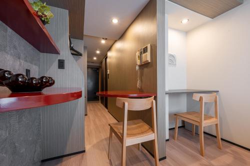 a small kitchen with a red counter and two stools at ACROSS Akihabara in Tokyo