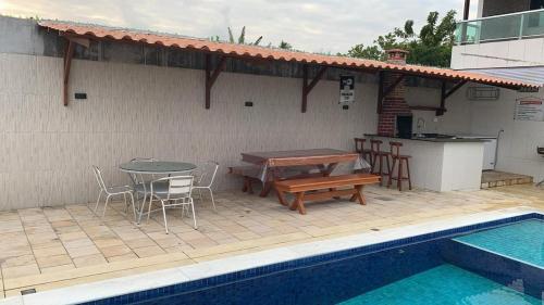 eine Terrasse mit Tisch und Stühlen neben einem Pool in der Unterkunft Casa Moderna em Nossa Senhora do Ó, Porto de Galinhas! in Ipojuca