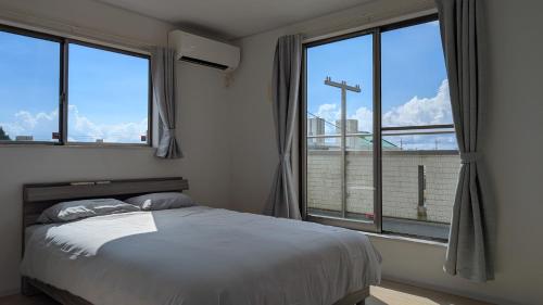 a bedroom with a bed and two large windows at Yomitan 4LDK house in Yomitan
