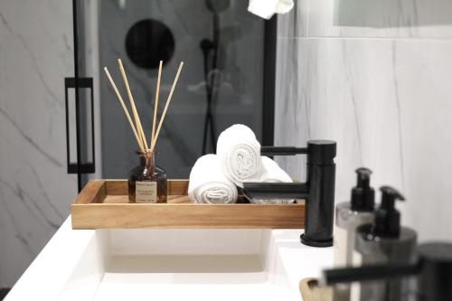 een badkamerwastafel met een houten dienblad met handdoeken bij A Marbled Touched Haven in Antwerpen