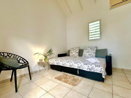 a bedroom with a bed and a chair at Kaz a Doudou La in Saint-François