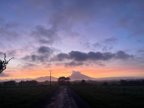 un chemin de terre avec une montagne au loin au coucher du soleil dans l'établissement Ocean Shores Warea, 