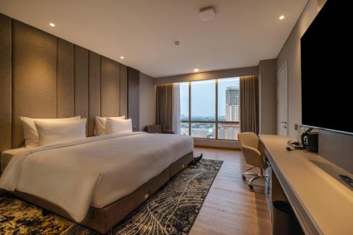 a hotel room with a large bed and a television at The Grand Platinum Jakarta in Jakarta