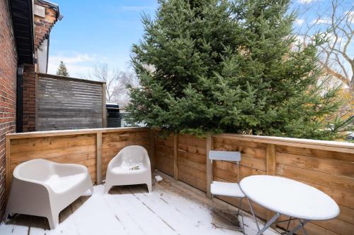 a patio with two white chairs and a tree at Modern Parkdale Getaway 1-Bedroom Parking in Toronto