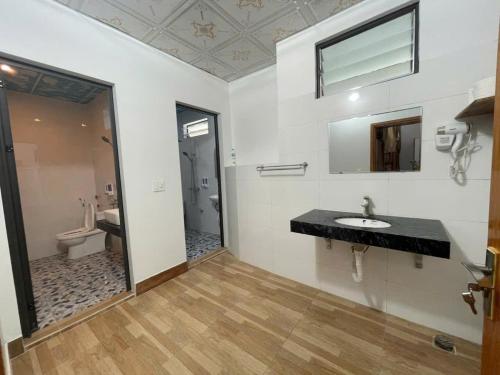 a bathroom with a sink and a toilet and a mirror at Sky Bay Lodge in Ha Giang