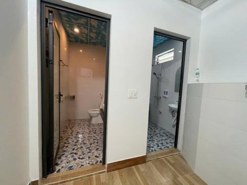 a bathroom with a toilet and a glass door at Sky Bay Lodge in Ha Giang