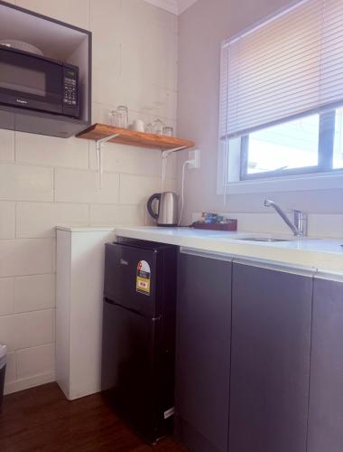 a kitchen with a black refrigerator and a sink at A1 Kaikoura Motel & Apartment in Kaikoura