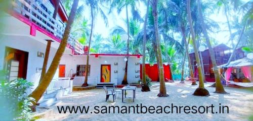 a patio with a table and chairs and palm trees at Samant Beach Resort in Malvan