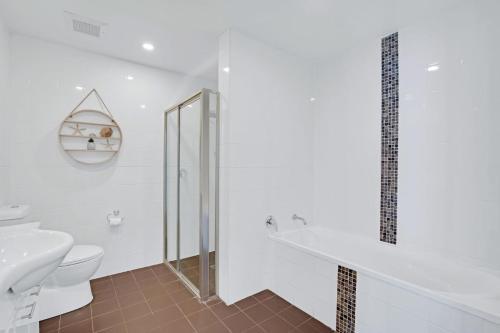 a white bathroom with a toilet and a sink at Reflections G01 On The Lake in Forster