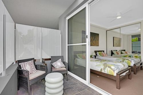 a bedroom with two beds and two chairs in it at Reflections G01 On The Lake in Forster