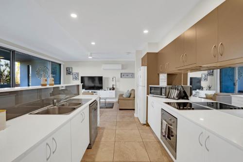 a large kitchen with white cabinets and appliances at Reflections G01 On The Lake in Forster