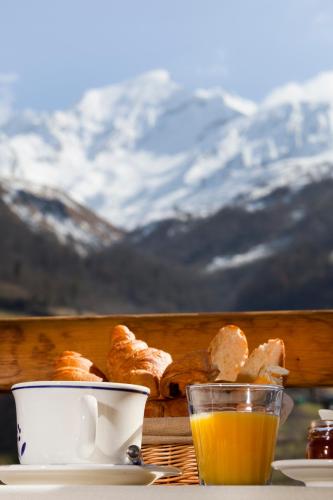 a table with a cup of orange juice and pastries at Hôtel Le Montaigu in Luz-Saint-Sauveur