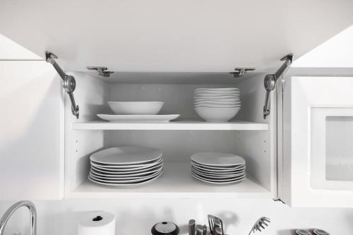 a kitchen cabinet with plates and dishes in it at Modern Lakefront Esc Stylish 2BR Condo with Patio in Toronto