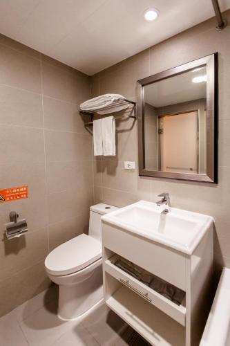 a bathroom with a sink and a toilet and a mirror at Hub Hotel Ximen-inn Kunming in Taipei