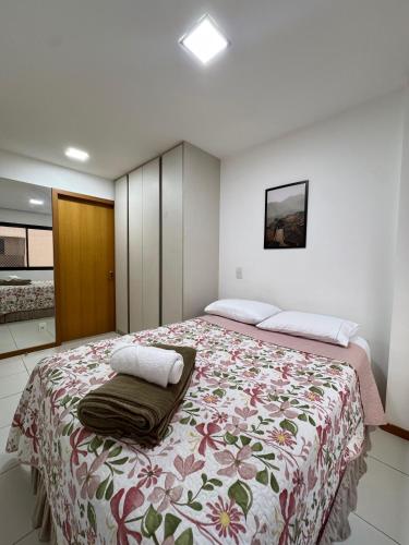 a bedroom with a large bed with a floral blanket at Via Brisa Apartment in Brasília