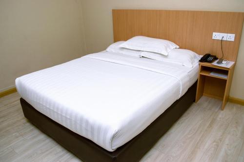 a large white bed in a room with a telephone at Labuan Avenue Hotel in Victoria Town