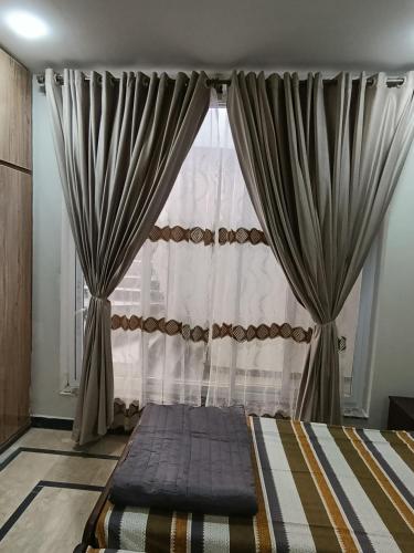 a bed in front of a window with curtains at RMT Residencia per room in Peshawar
