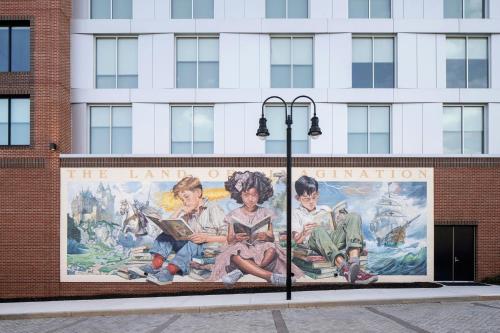 a mural of children reading books on the side of a building at Trilith Guesthouse, Fayetteville, GA, a Tribute Portfolio Hotel in Fayetteville