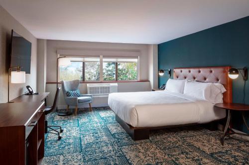 a bedroom with a bed and a desk and a window at Four Points by Sheraton Norwood Conference Center in Norwood
