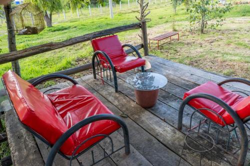 three chairs and a table on a wooden deck at Cabañas Santa Teresa de las Flores in Sogamoso