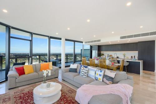 a living room with two couches and a kitchen at Spacious Two Level 4BR at Sydney Olympic Park with Best View in Sydney