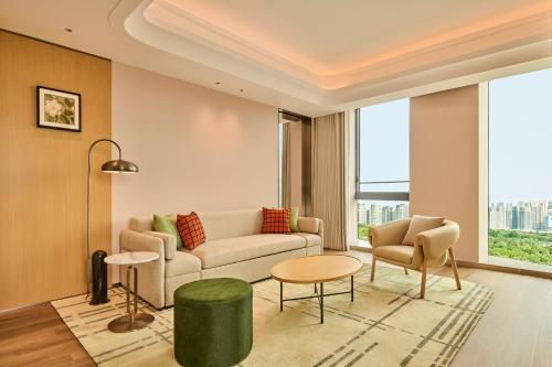 a living room with a couch and a table and chairs at Hilton Garden Inn Chongqing Yubei Central Park in Chongqing