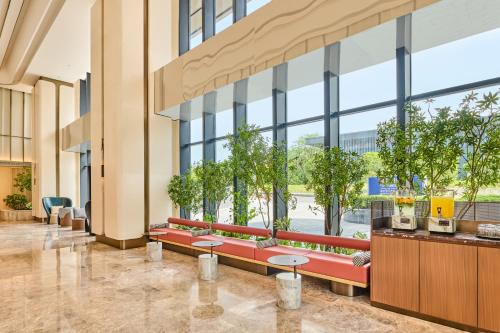 a lobby with benches and trees in a building at Hilton Garden Inn Chongqing Yubei Central Park in Chongqing