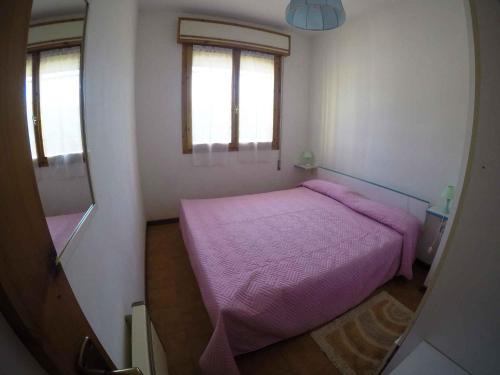 een kleine slaapkamer met een paars bed en 2 ramen bij Apartment in Rosolina Mare 34551 in Rosolina Mare