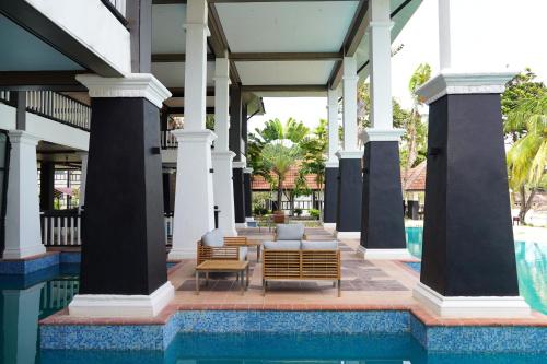 an outdoor patio with chairs and a pool at a resort at Peridot By The Sea Redang in Redang Island