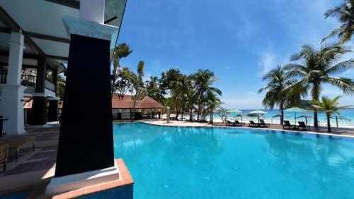 a large swimming pool with palm trees and the ocean at Peridot By The Sea Redang in Redang Island