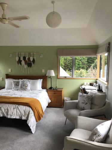 a bedroom with a bed and a chair and window at Woodland Glen Lodge B&B in Hokitika