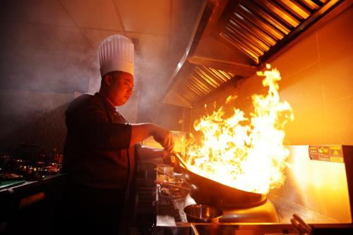 a chef cooking in a pot filled with flames at TRIMULIA Hotel in Sihanoukville