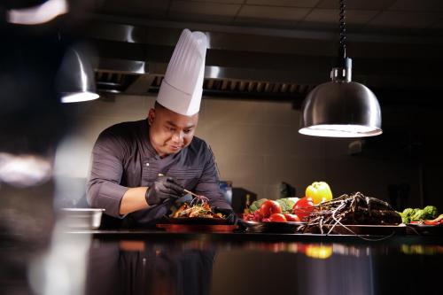 a chef preparing food on a plate in a kitchen at TRIMULIA Hotel in Sihanoukville