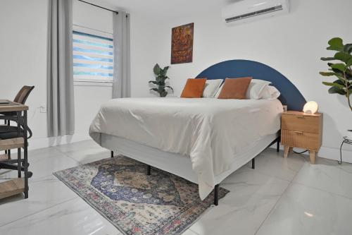 a white bedroom with a bed with a blue headboard at Suite Azul Miami - Private Guest Suite with Patio, Free Parking, Near Wynwood and Beaches in Miami