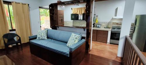 a living room with a blue couch in a kitchen at Charming Small House, Near the beach & Waterfalls in Platanillo