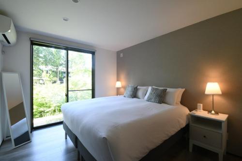 una camera da letto con un letto grande e una grande finestra di Greyton A - Brand new chic bright spacious 2BR a Wada