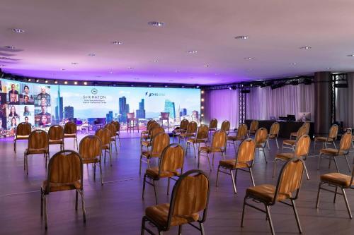 a room with a bunch of chairs and a screen at Sheraton Milan Malpensa Airport Hotel & Conference Centre in Ferno