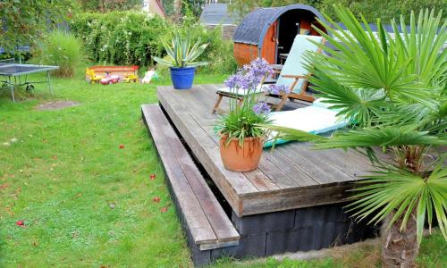 a wooden deck with plants on it in a yard at Berlinurlaub im Grünen, Pool-Whirlpool beheizt, Sauna, Spielplatz, Grill, 3 Doppelzimmer in Blankenfelde