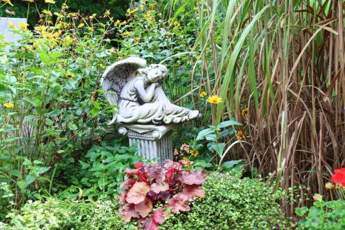 a statue of an angel sitting in a garden at Berlinurlaub im Grünen, Pool-Whirlpool beheizt, Sauna, Spielplatz, Grill, 3 Doppelzimmer in Blankenfelde