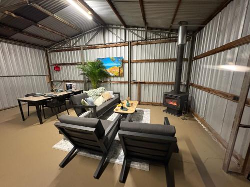 a living room with a couch and chairs and a stove at Ukiyo Nature Retreat in Fingal