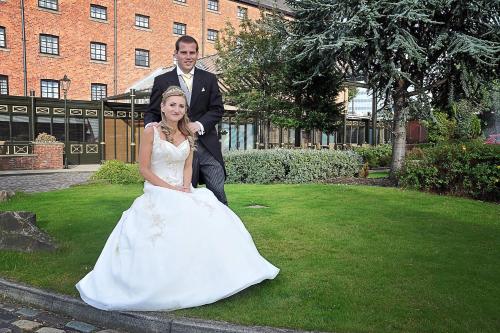 a bride and groom posing for a picture in front of a building at Manchester Marriott Victoria & Albert Hotel in Manchester