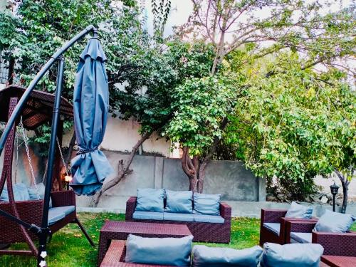 a patio with chairs and a swing and an umbrella at Shah Hujra Guest House Skardu in Skardu