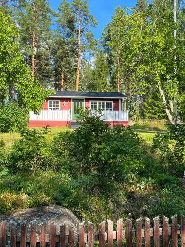 a red and white house behind a fence at Cosy Forest Cabin Near Bollnäs in Bollnäs
