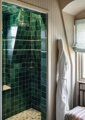 a green tiled shower in a bathroom with a robe at Le Petit Pali St Helena in St. Helena