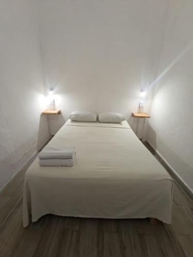 a bedroom with a white bed with two lights on it at Casa Tortuga Azul in Palenque
