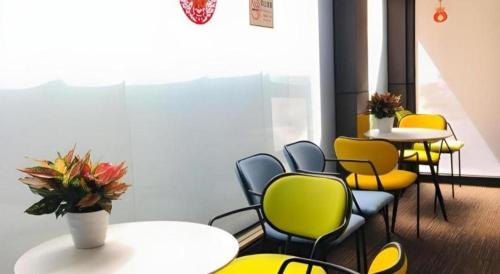 a waiting room with tables and yellow chairs at My Pleasant Hotel in Shenzhen