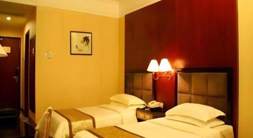 two beds in a hotel room with yellow walls at Quanzhou Royal Prince Hotel in Quanzhou