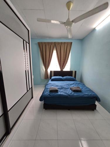 a bedroom with a bed with blue walls and a window at Irah Homestay in Kuantan