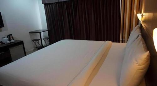 a bedroom with a large white bed and a desk at Mukdaview Hotel in Mukdahan